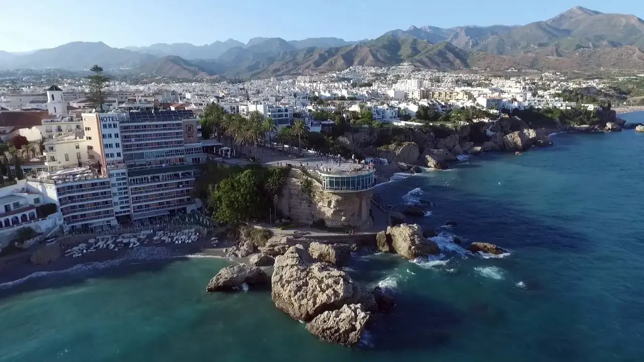 Vista aérea del Balcón de Europa y el hotel junto a la playa, con la sierra al fondo