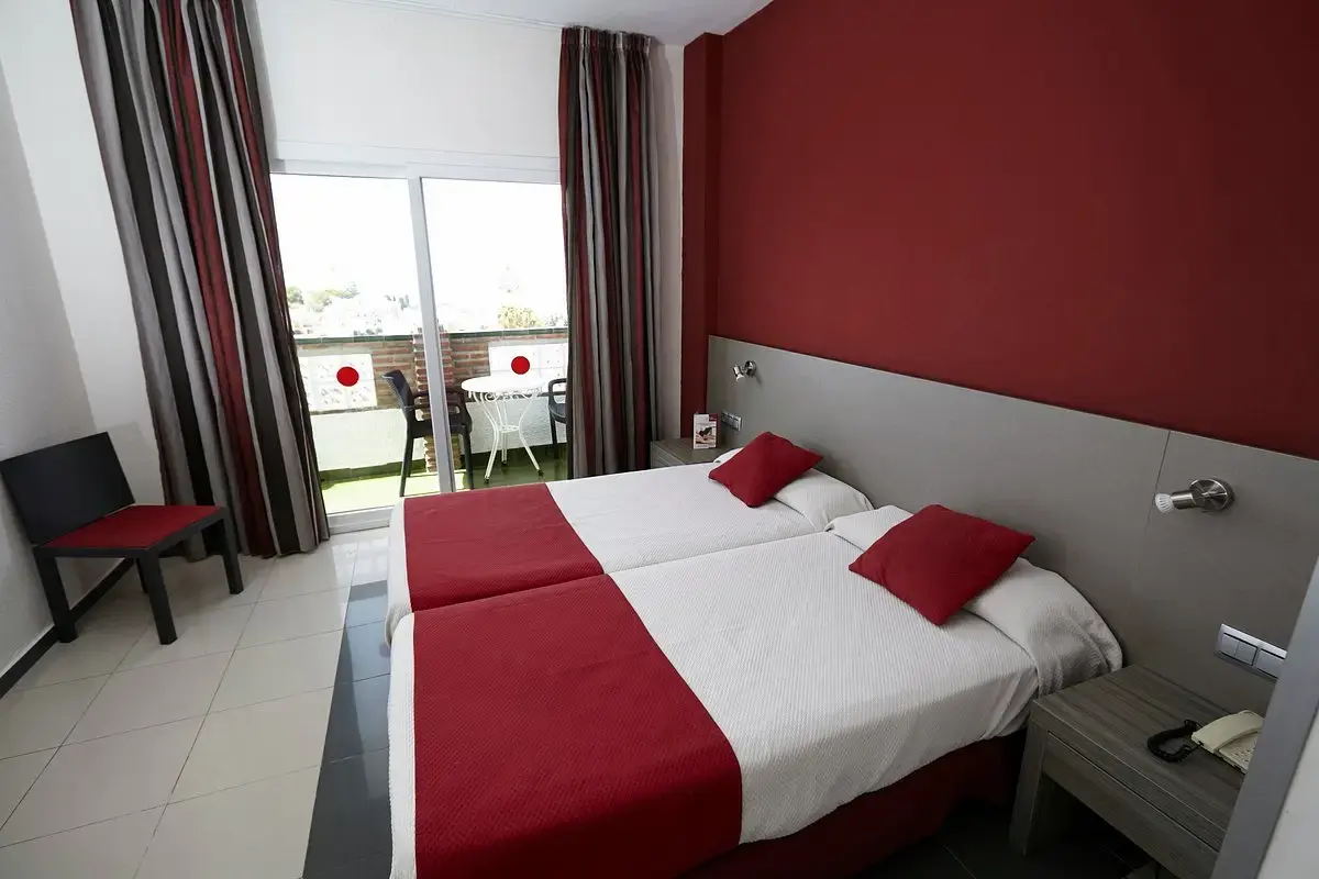 Habitación con dos camas individuales juntas, cabecero gris y salida a la terraza
