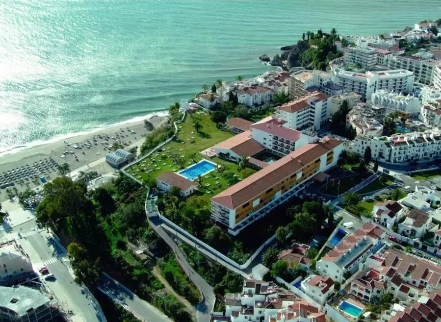 Vista aérea de Nerja con un gran hotel, jardín con piscina y la playa junto al mar