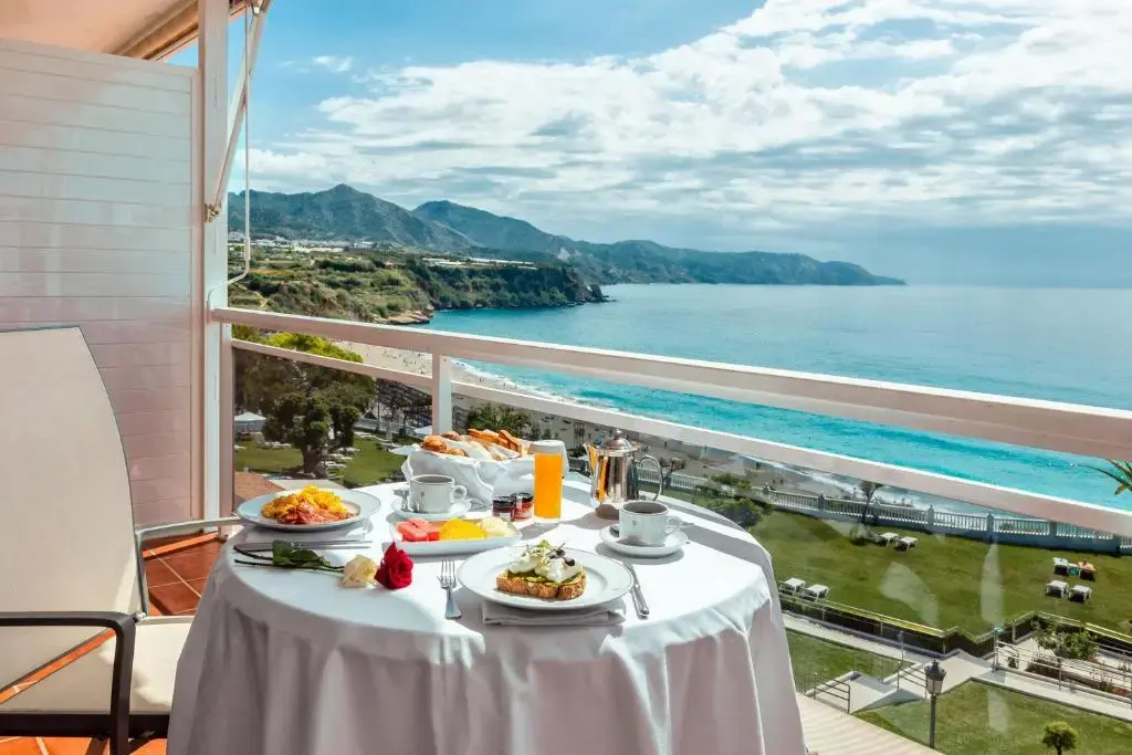 Desayuno servido en una terraza con vistas al mar, la playa de Burriana y los acantilados