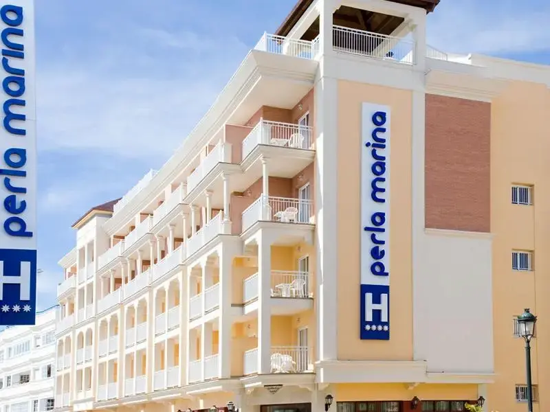 Fachada del Hotel Perla Marina con balcones blancos y su letrero vertical azul