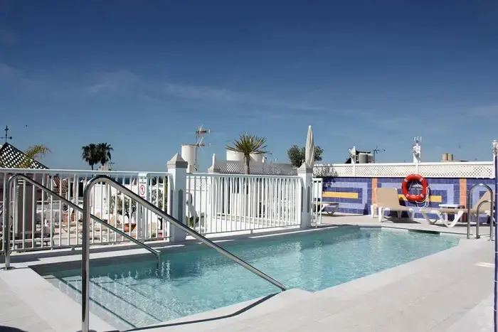 Piscina de la azotea del Hotel Puerta del Mar con barandilla blanca y tumbonas