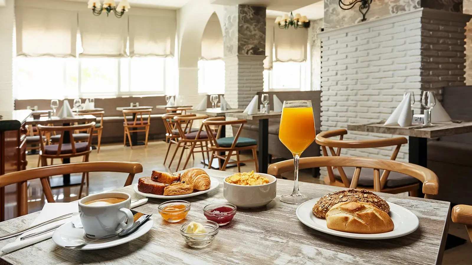 Desayuno con café, zumo de naranja, bollería y pan en el comedor del hotel