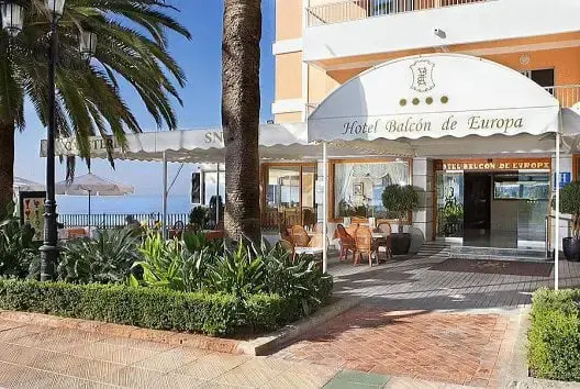 Entrada del Hotel Balcón de Europa bajo un toldo blanco, junto a la terraza y los jardines