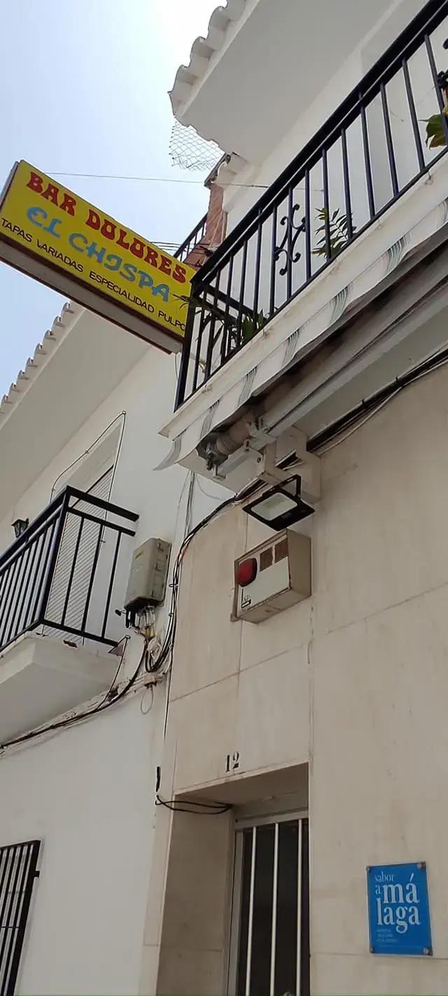 Rótulo amarillo de tapas variadas y especialidad en pulpo sobre una calle blanca