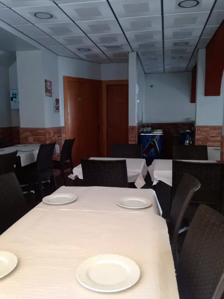Comedor con mesas de manteles blancos, platos preparados y sillas oscuras
