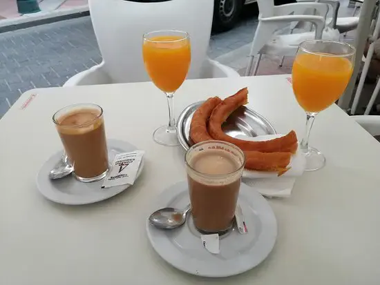 Desayuno con churros, dos cafés con leche y dos zumos de naranja en la terraza