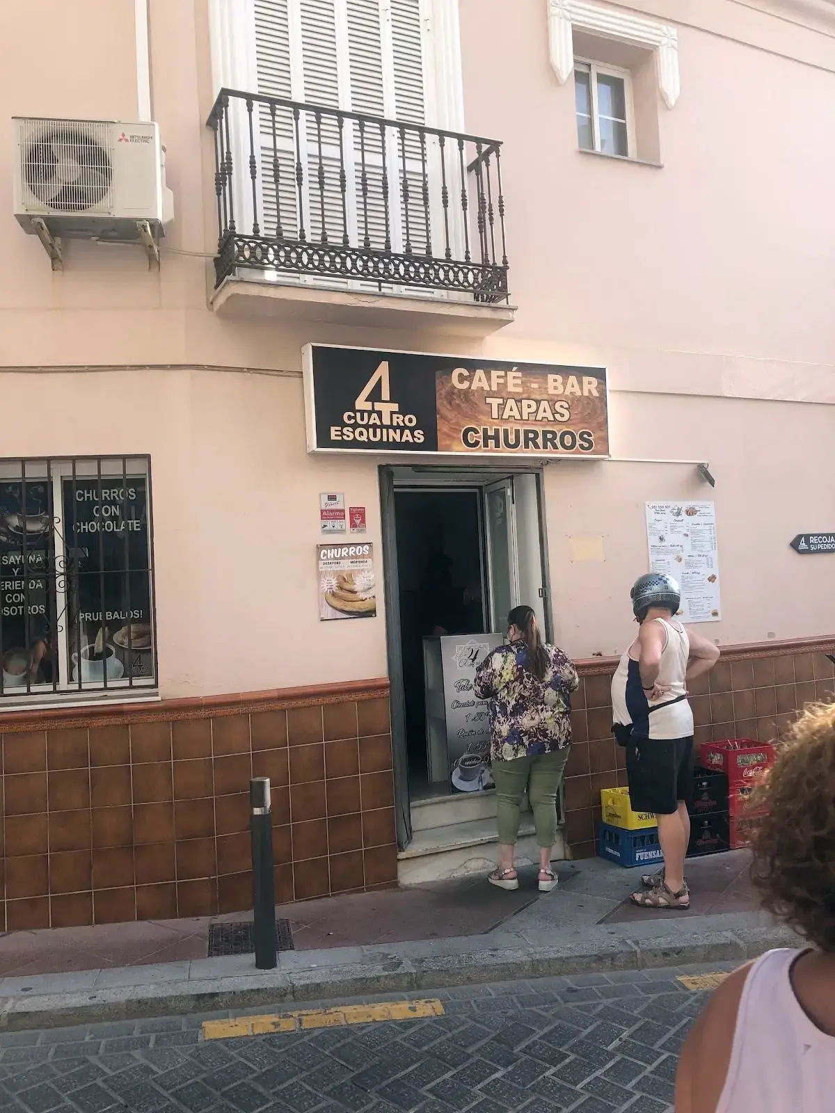 Entrada con el rótulo Café-Bar, Tapas, Churros y clientes esperando en la puerta