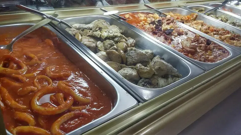 Bandejas de comida casera en la vitrina: calamares en salsa de tomate, pollo y guisos