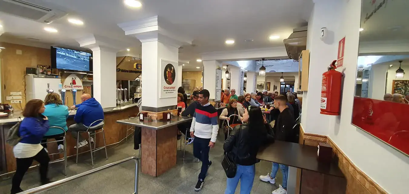 Interior de El Pulguilla lleno de gente junto a la barra y las mesas altas
