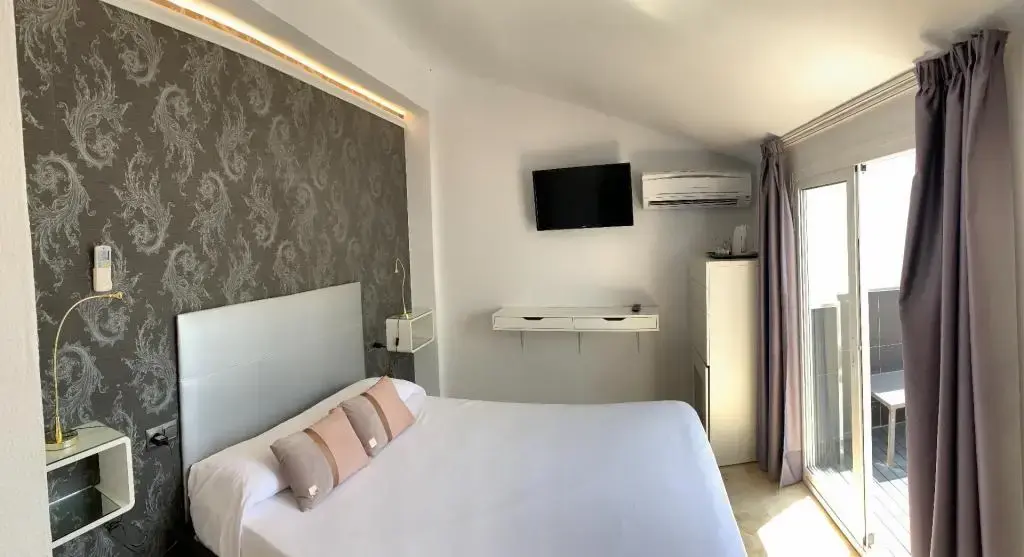 Habitación doble con papel pintado gris, televisión en la pared y salida a la terraza