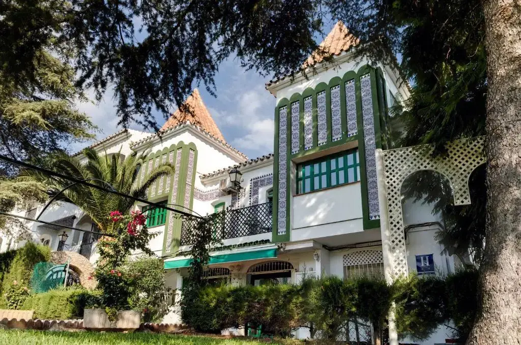 Edificio del Hostal Alegre con torres de tejado a cuatro aguas y azulejos verdes y blancos