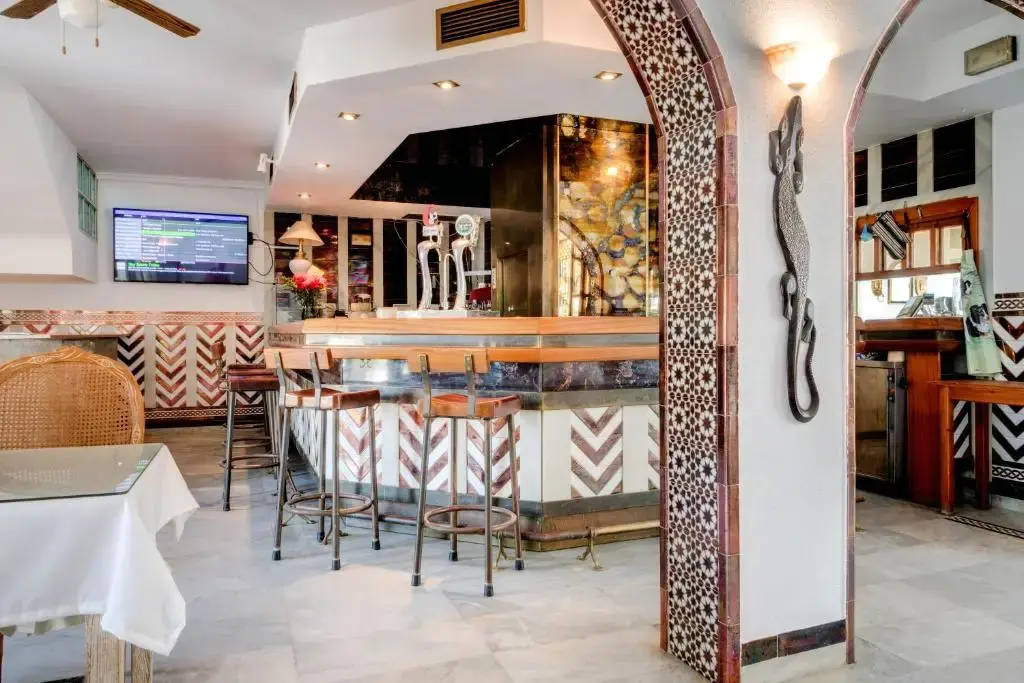 Bar con barra de azulejos, taburetes altos y arcos decorados con cerámica