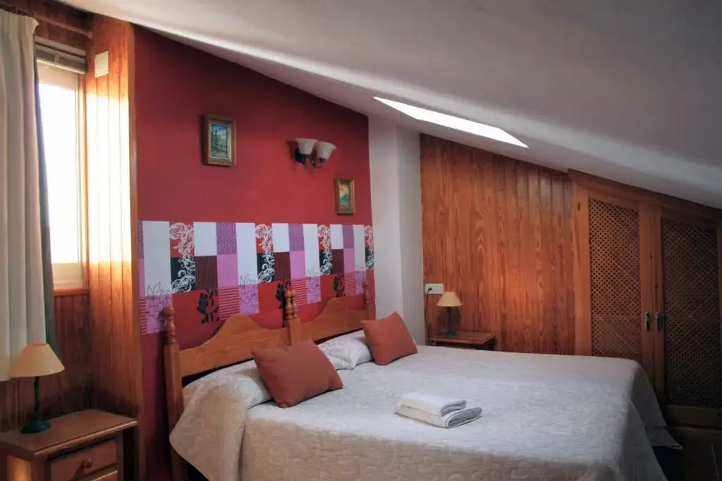 Habitación abuhardillada con cama de matrimonio, claraboya y paredes de madera