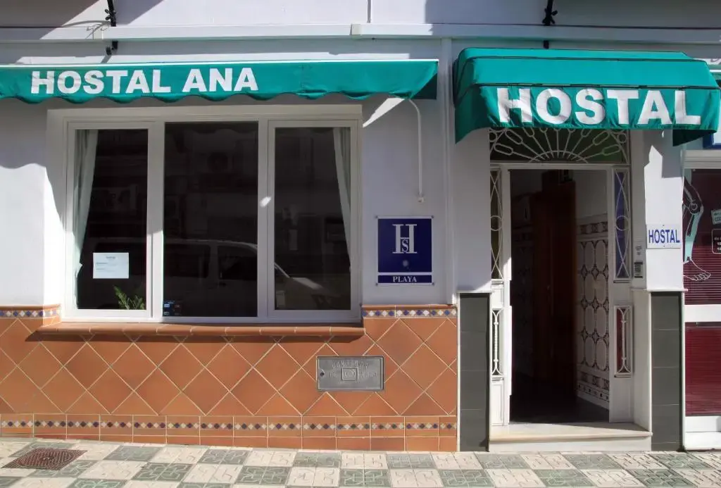 Fachada del Hostal Ana con toldos verdes, zócalo de azulejos y placa azul de hostal