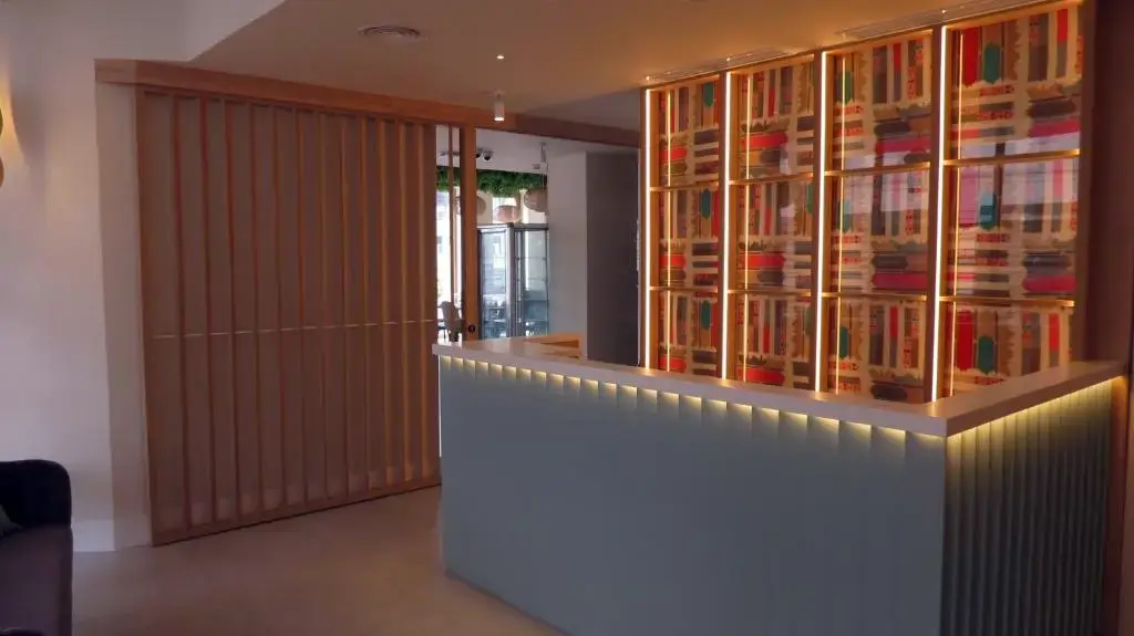 Mostrador de recepción iluminado con luz led y estantería de colores al fondo