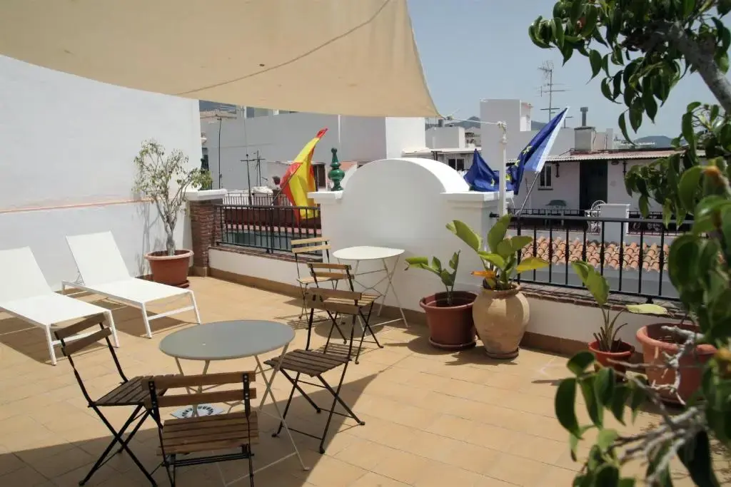 Azotea con toldo de vela, tumbonas blancas, mesas plegables y plantas en macetas