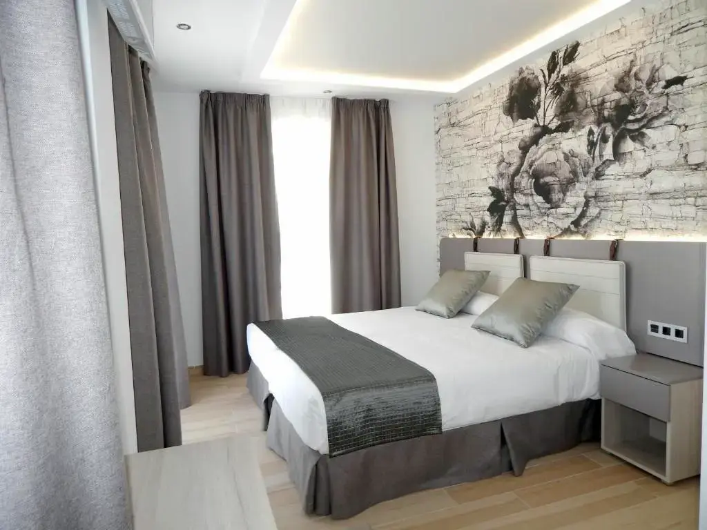 Habitación con cama de matrimonio, mural de rosas en tonos grises y cortinas gruesas