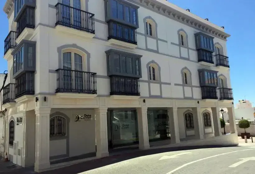 Edificio blanco del hostal en la calle la Cruz, con miradores grises y balcones de forja