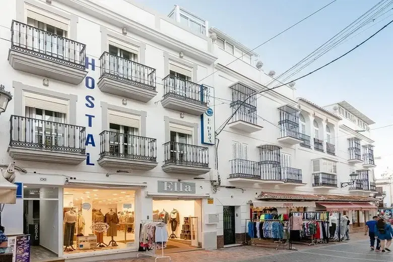 Fachada del Hostal Luna de Nerja con balcones de forja sobre tiendas de ropa