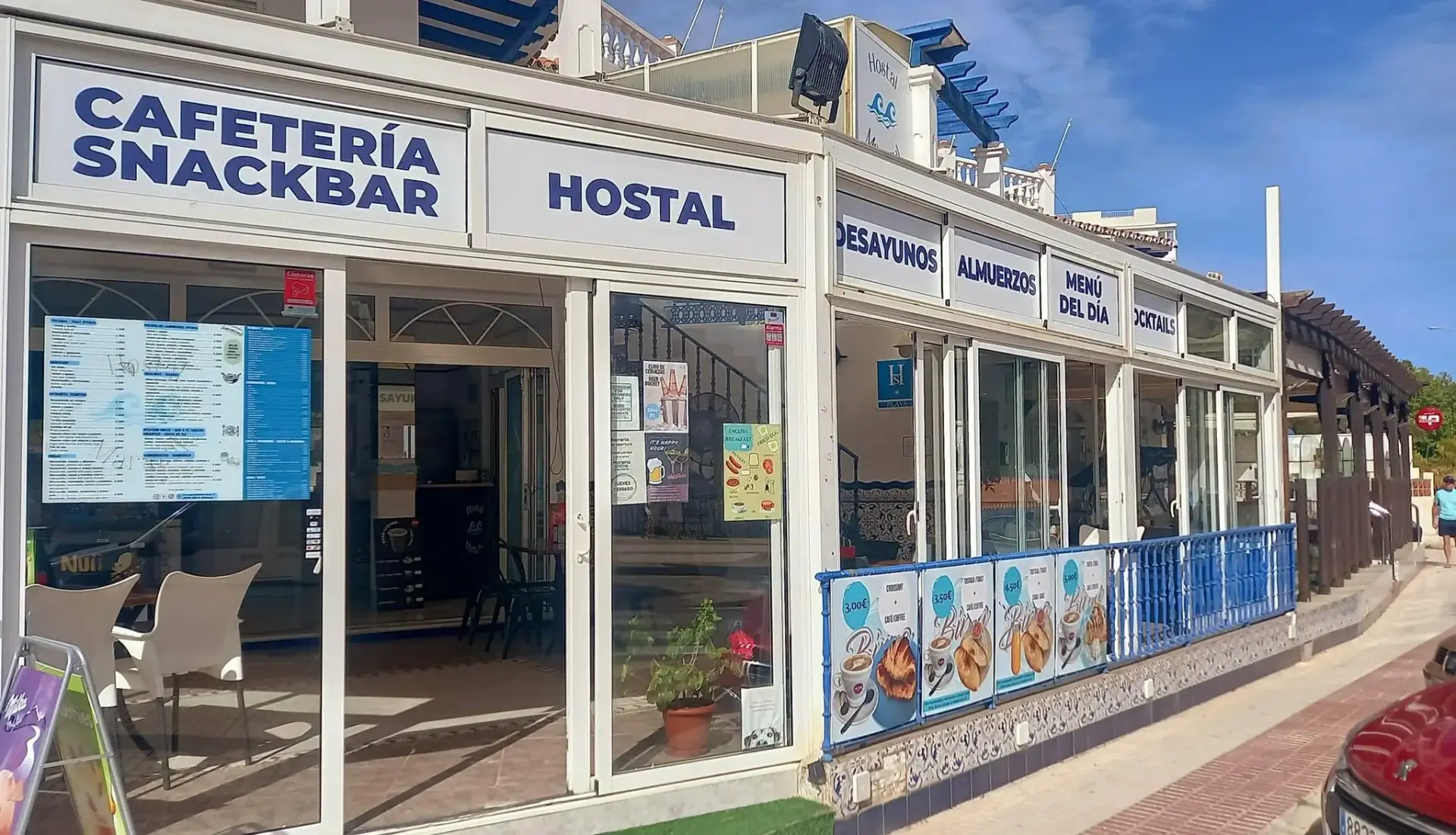 Cafetería snack bar del hostal con carteles de desayunos, almuerzos y menú del día