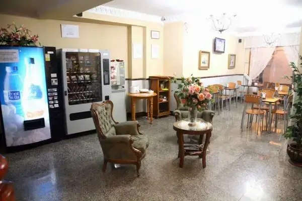 Sala con máquinas expendedoras, sillones tapizados y mesas de cafetería al fondo