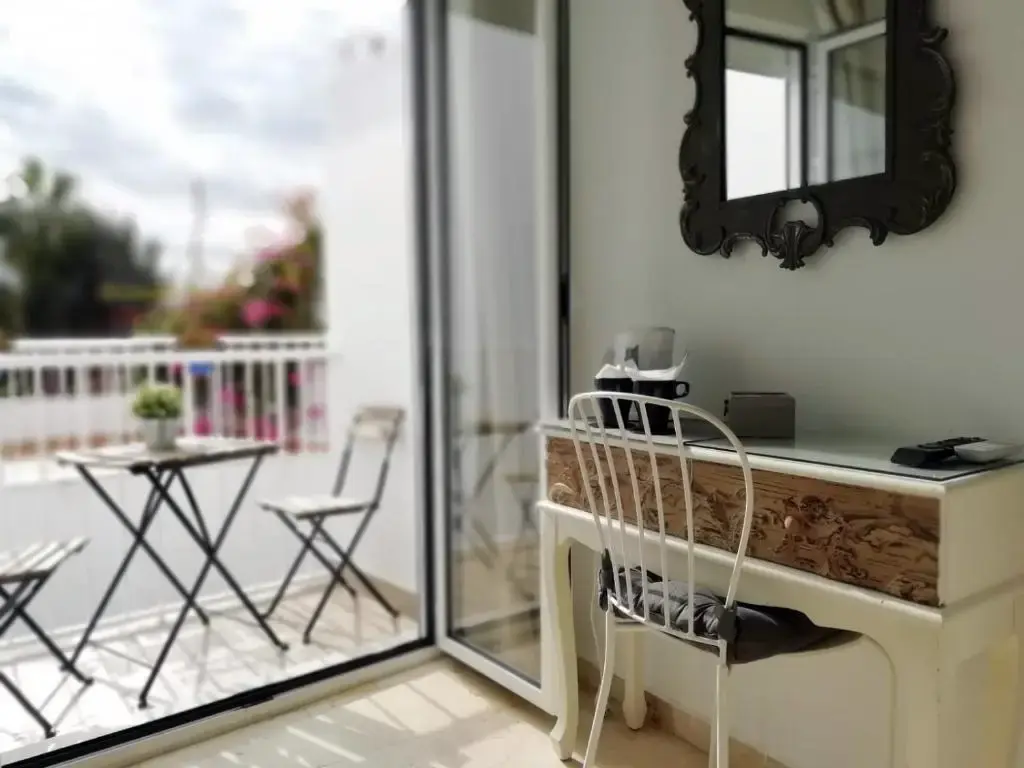 Escritorio con espejo junto a la puerta del balcón, con mesita y sillas plegables fuera