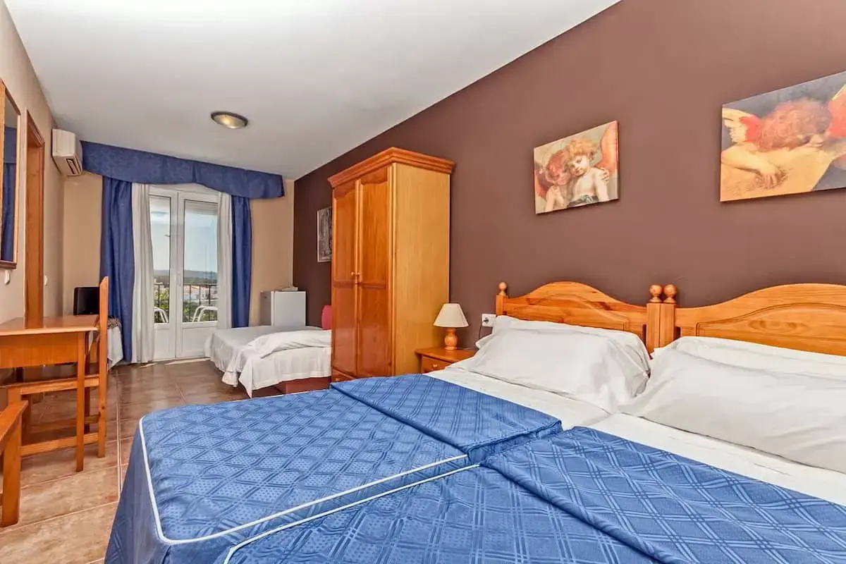 Habitación con dos camas individuales juntas, armario de madera y una cama supletoria