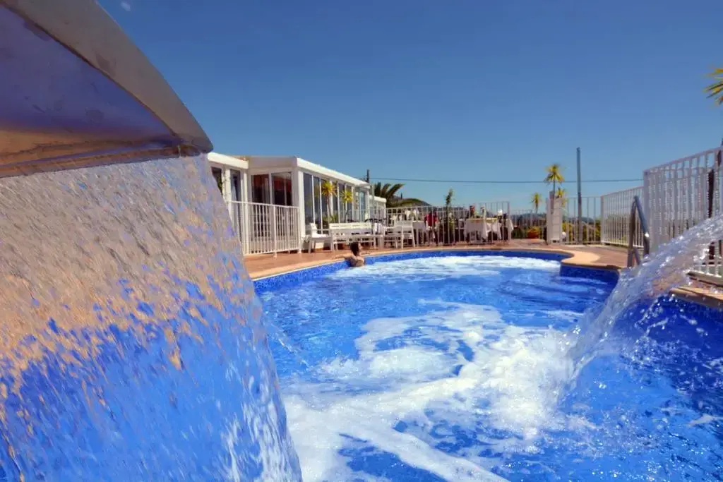 Chorro de agua cayendo en la piscina, con la terraza acristalada del comedor al fondo