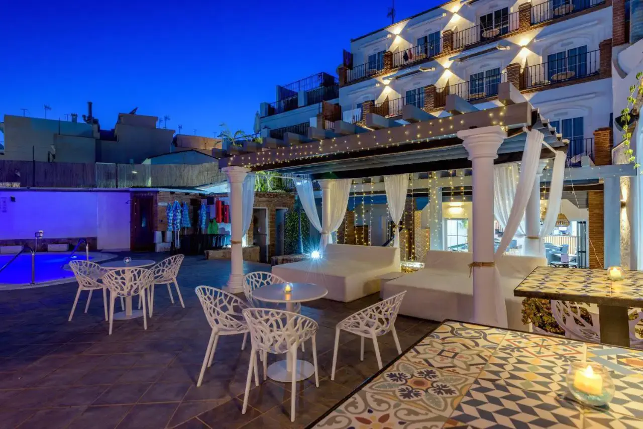 Terraza de noche con camas balinesas, guirnaldas de luces y mesas con velas