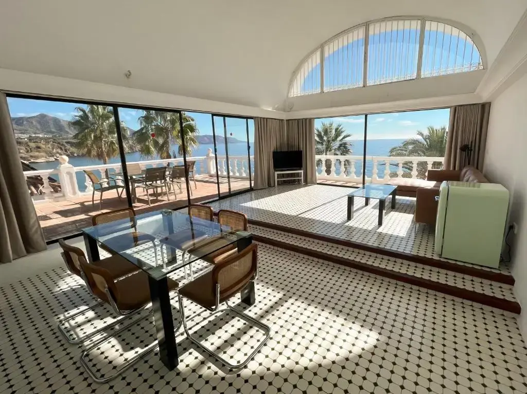 Salón amplio con comedor de cristal y ventanales abiertos a la terraza y al mar