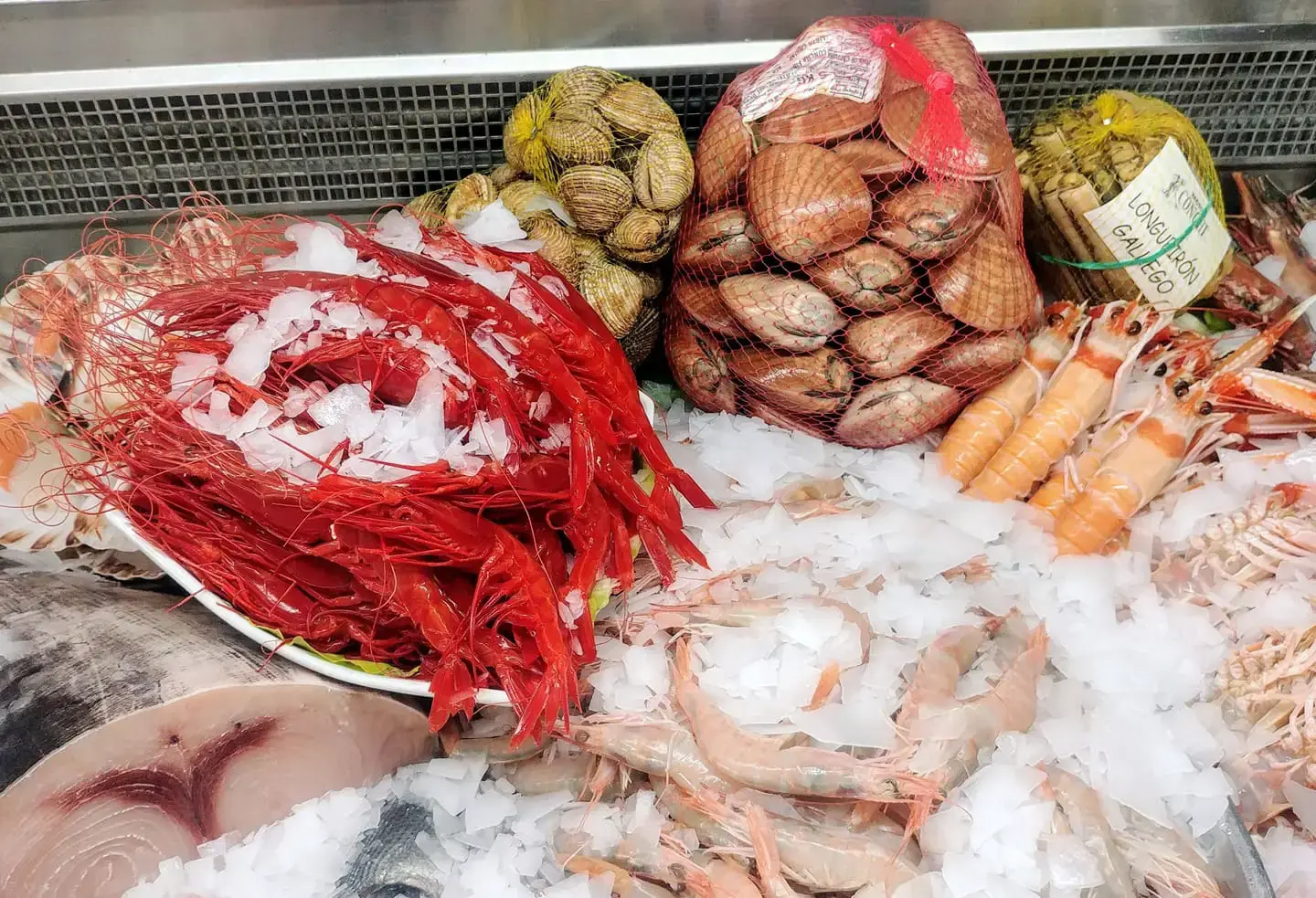 Expositor de marisco en hielo con gambas rojas, vieiras, almejas y longueirón gallego