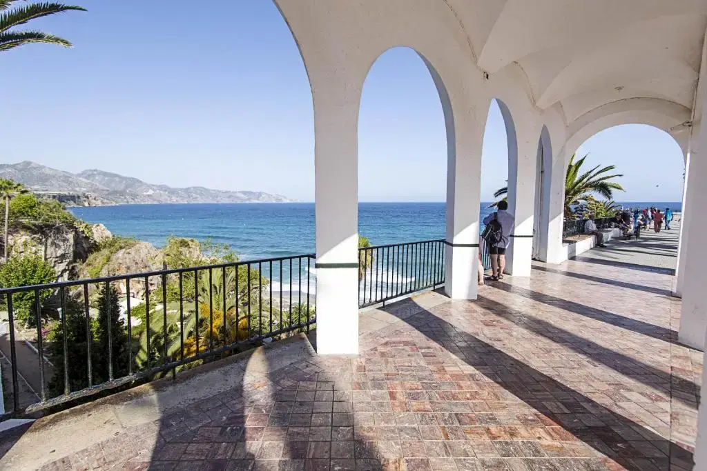Arcos blancos del Balcón de Europa con barandilla de forja y vistas al mar y la costa
