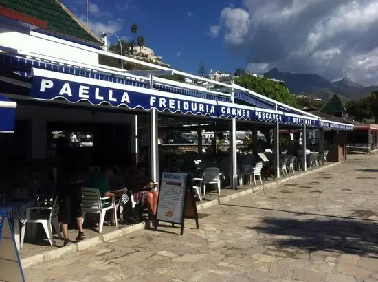 Toldo azul con paella, freiduría, carnes y pescados sobre la terraza del paseo