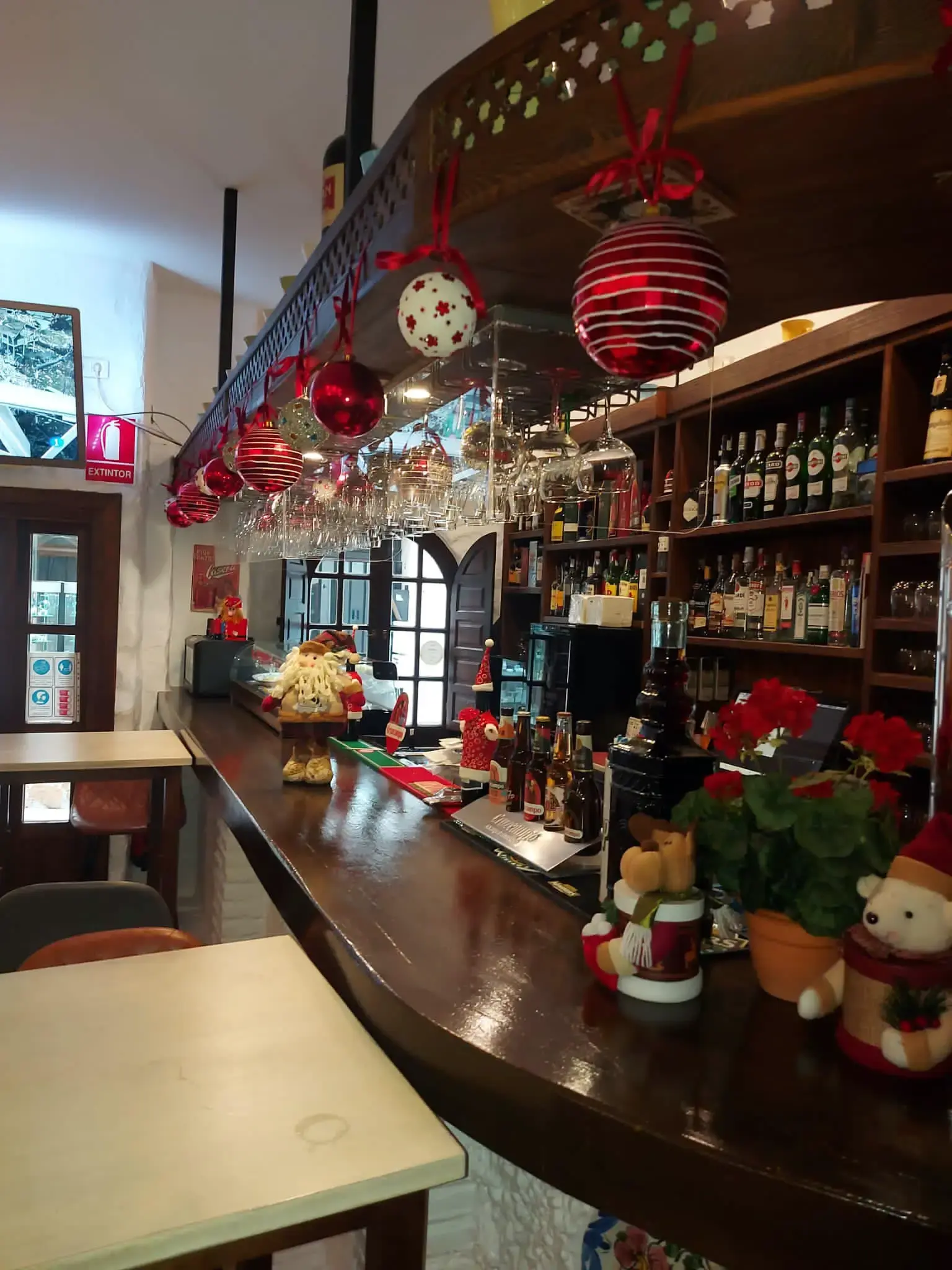 Barra de madera con estanterías de bebidas y adornos navideños colgados en el restaurante