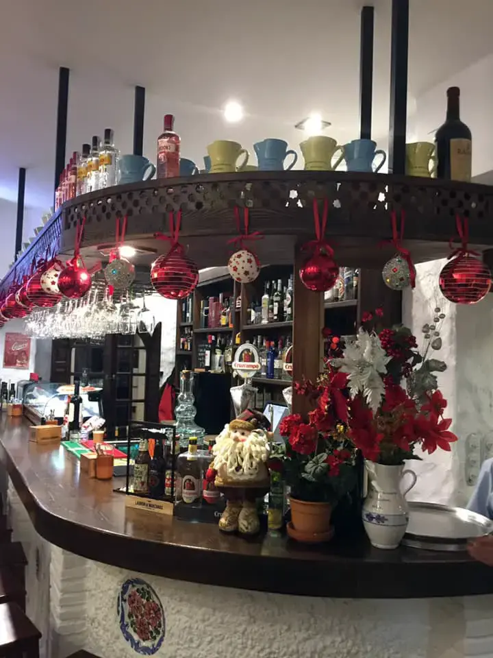 Barra curva con tazas sobre la repisa, botellas y flores rojas de Pascua