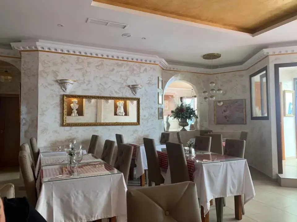 Salón con paredes estucadas, espejo dorado y mesas con mantel blanco