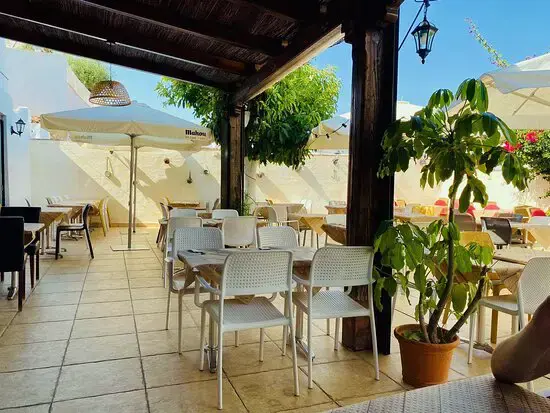 Terraza de verano soleada con sillas blancas, sombrillas y plantas