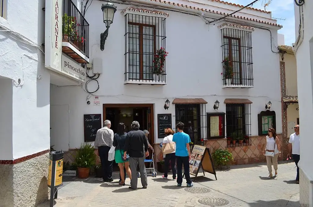 Grupo de personas ante la puerta del restaurante en una calle blanca del centro