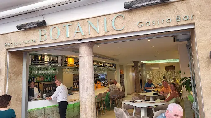 Entrada del Botanic Gastro Bar con la barra iluminada y clientes en las mesas