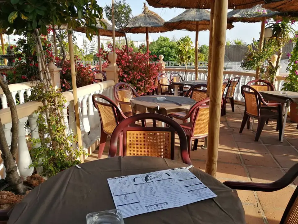 Mesa con la carta en la terraza, entre buganvillas y balaustrada blanca