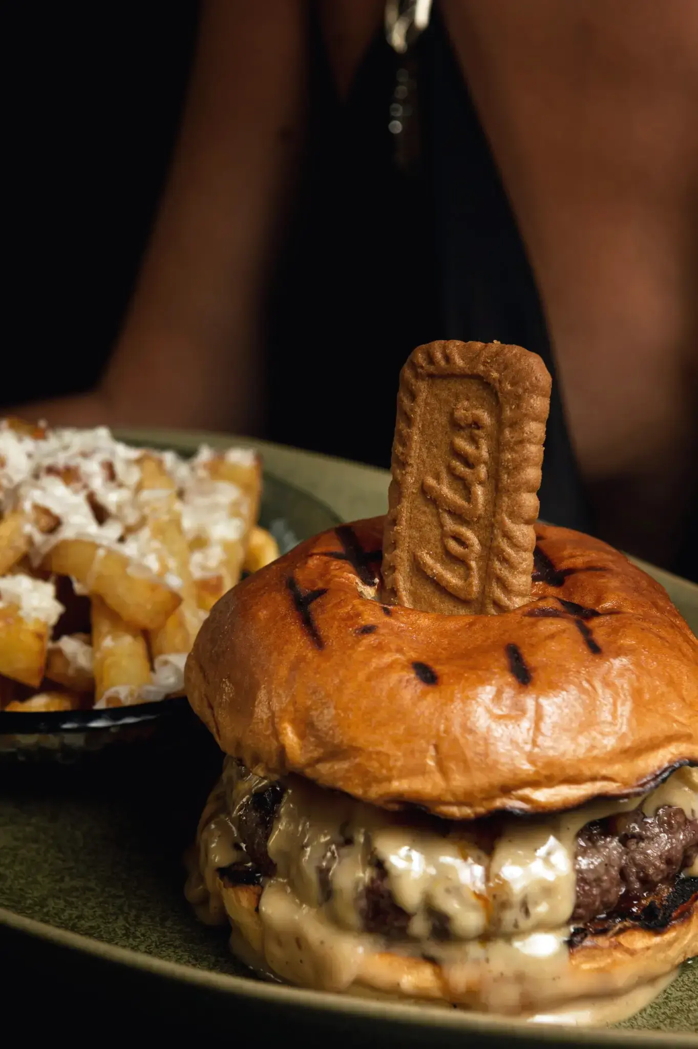 Hamburguesa con queso fundido y galleta de canela, con patatas fritas al lado