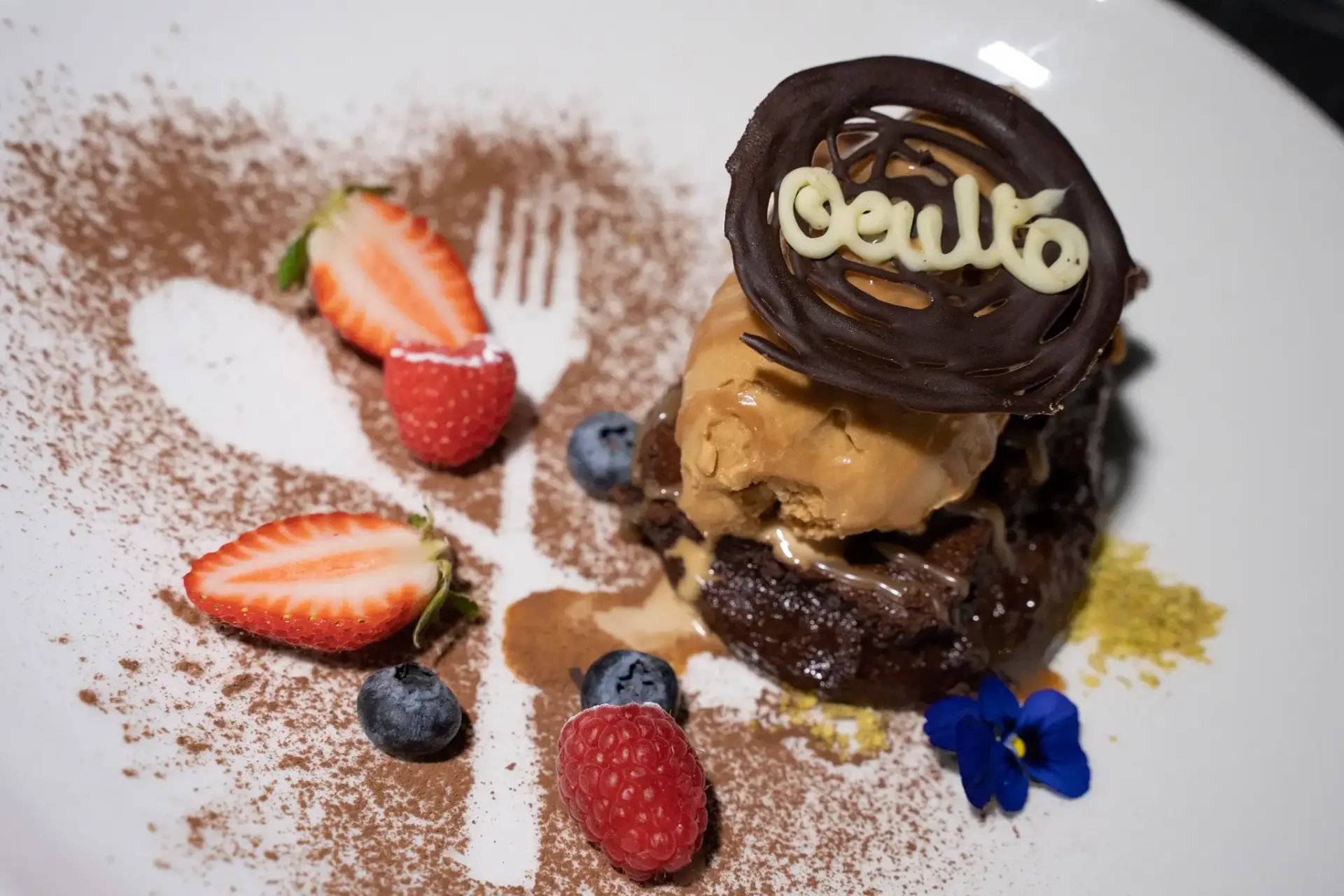 Brownie con helado, fresas, arándanos y disco de chocolate con el nombre Oculto