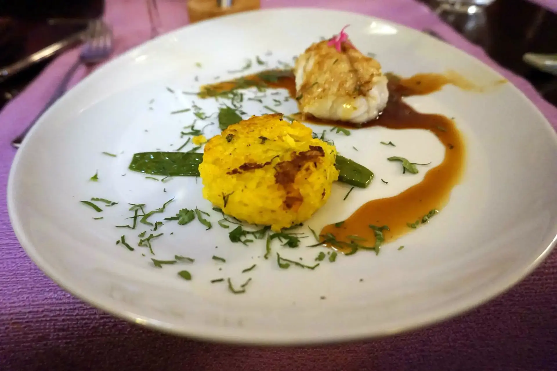 Arroz dorado con pescado blanco, tirabeques y salsa, servido en plato hondo