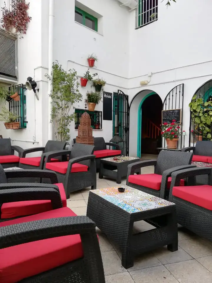 Patio blanco de la tetería con sillones rojos, arcos verdes y geranios
