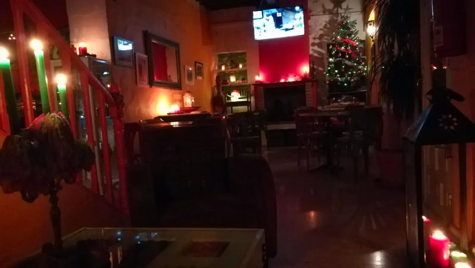 Interior por la noche con velas, árbol de Navidad iluminado y una pantalla de televisión