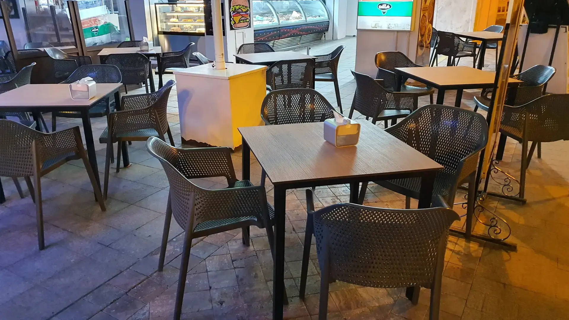 Mesas cuadradas y sillas grises de la terraza vacía por la noche