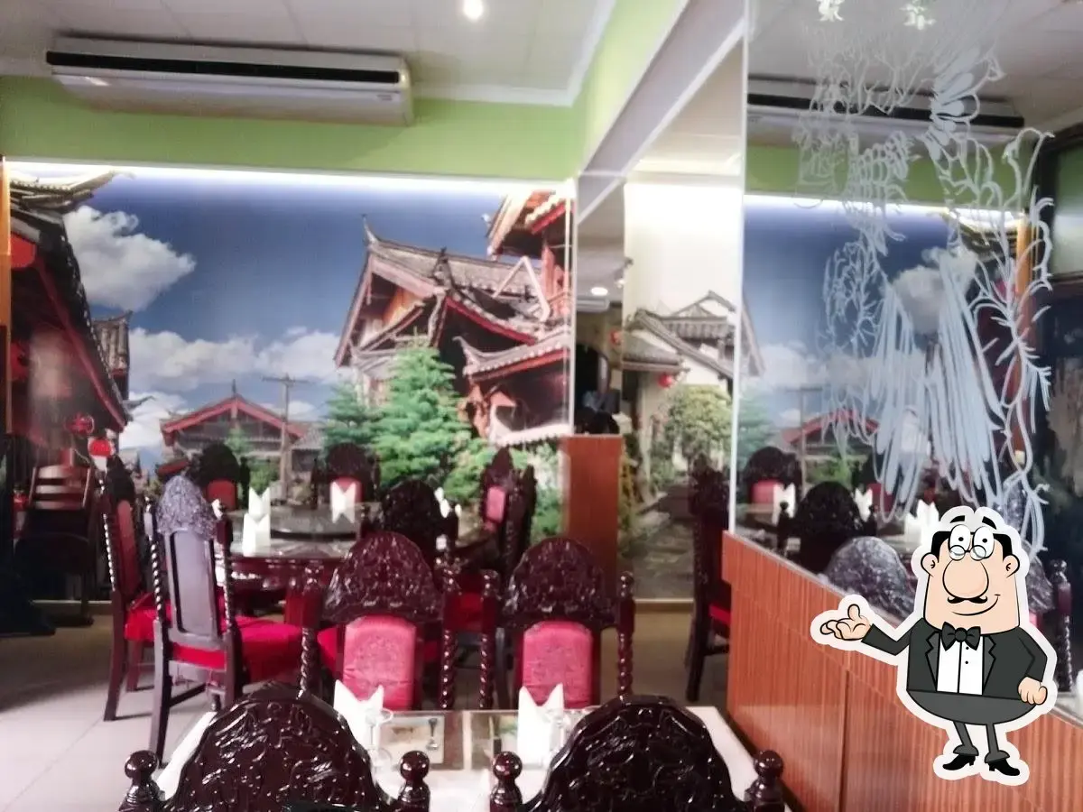 Mesas con sillas tapizadas en rojo frente a un mural de casas tradicionales chinas