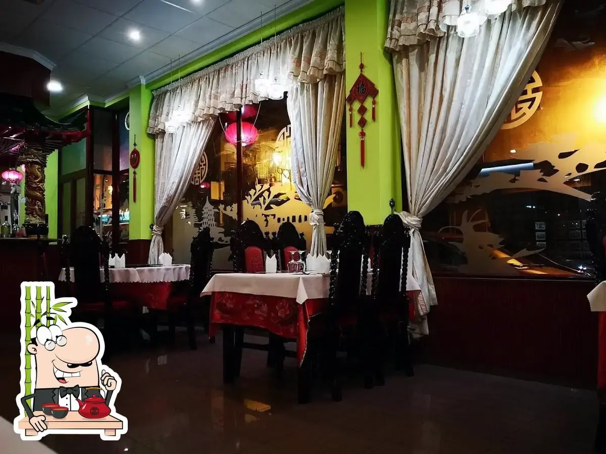 Mesas junto a ventanales con cortinas y adornos chinos rojos, de noche