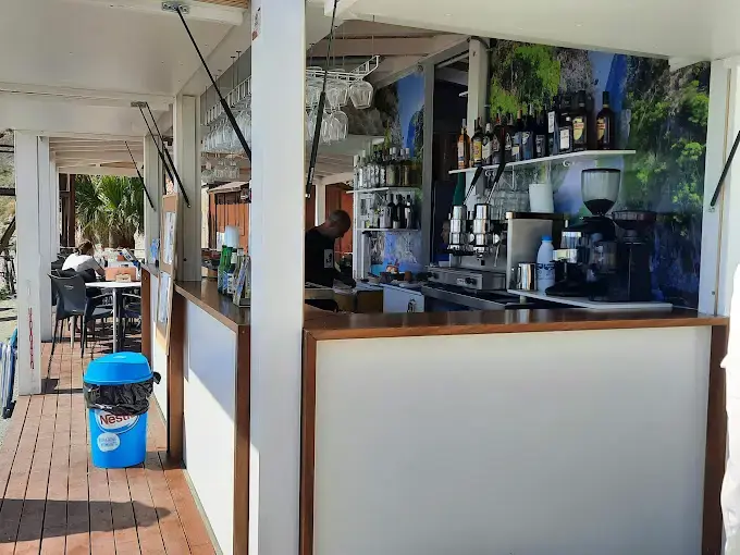 Barra del Chiringuito Playa Maro con cafetera, botellas y copas colgadas